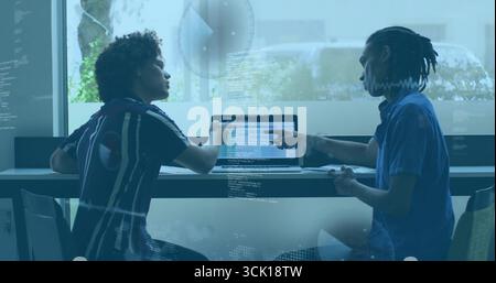 Developers collaborating on laptop typing code in meeting room, with glass reflections Stock Photo