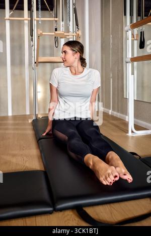 A woman performs pilates exercises on a reformer machine inside a ...