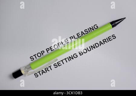 Concept of stop people pleasing and start setting boundaries with pen write on book isolated on Wooden Table. Stock Photo