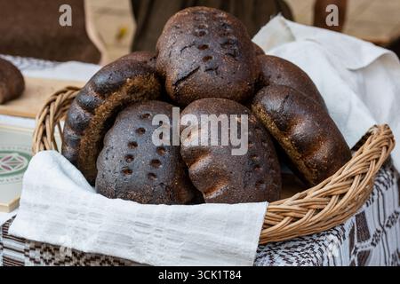 Homemade black rye cereal bread with seeds and ear of corn or wheat in a wicker basket with linen in a traditional street food market Stock Photo