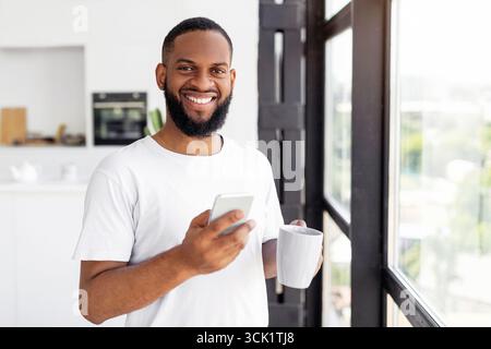 Black man using his smartphone drinking coffee Stock Photo