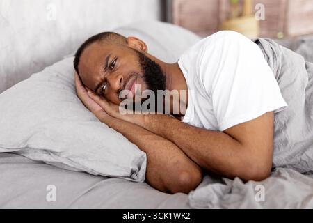 Black man lying in bed and thinking Stock Photo