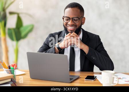 Smiling black man watching video on computer Stock Photo
