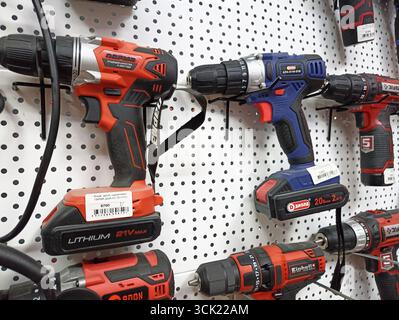 Assorted power drills displayed on pegboard for sale in hardware store. Stock Photo
