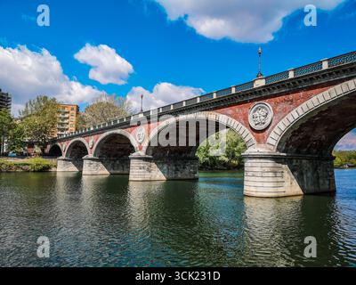 A scenic view of Ponte Isabella, a historic bridge with red brick arches and white stone accents, crossing the Po River in Turin, Italy. The calm, gre Stock Photo