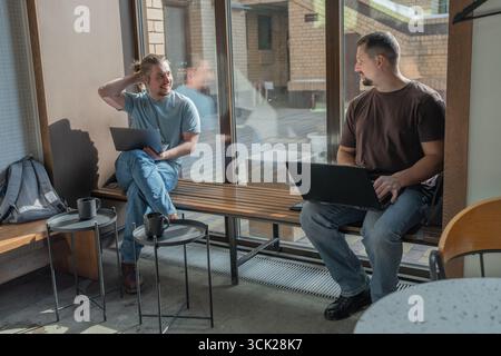 Two laughing It Software engineers working on project and programming in coffee shop. Successful start up project concept. Stock Photo