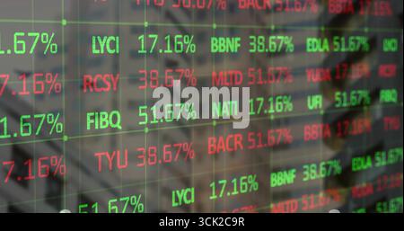 Displaying ticker overlay on glass panel in trading room, with symbols, percentages and monitors Stock Photo