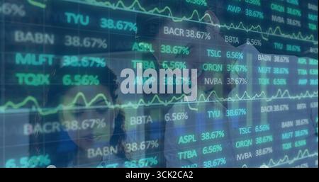 Analysts wearing business attire analyzing stock tickers in modern office, with digital screen Stock Photo