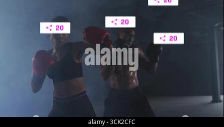 Sparring adult woman and man maintaining stances in dark hazy gym, with red, black boxing gloves Stock Photo