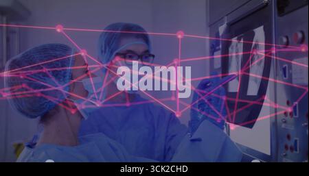Medical doctors in scrubs masks gloves viewing X-ray on screen in hospital lab with pink overlay Stock Photo