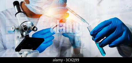 Close up of scientist working in laboratory using microscope and pipette to transfer blue liquid into test tube, representing research, analysis, chem Stock Photo