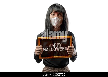 Indonesian southeast asian transgender man dressed as a woman wearing a bloody face mask and showing the text of Happy Halloween on a blackboard. Conc Stock Photo