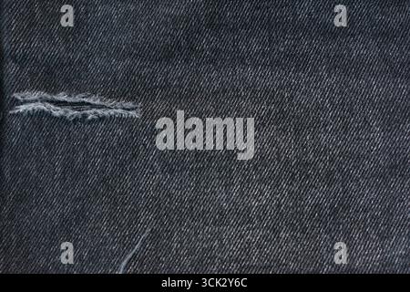 Close-up Dark Jeans with hole torn, Ripped Destroyed denim jean, Detail of Classic Dark Jeans Fabric. Stock Photo