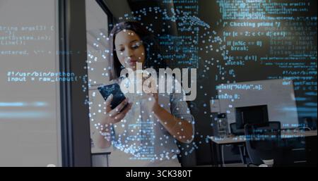 Woman wearing shirt scanning smartphone through glass partition in open office, coffee cup and code Stock Photo