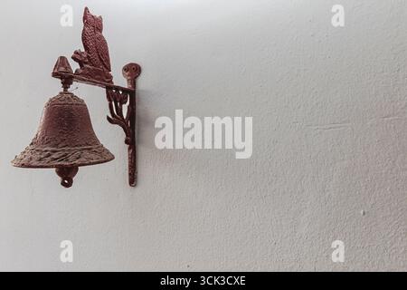 Vintage metal bell with rusty surface mounted on a textured wall. Suitable for themes of architecture, rustic decoration, heritage, and historical des Stock Photo