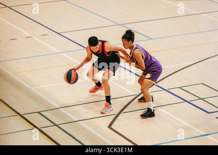 Two young female basketball players in a fierce game engage in close action on court. Stock Photo