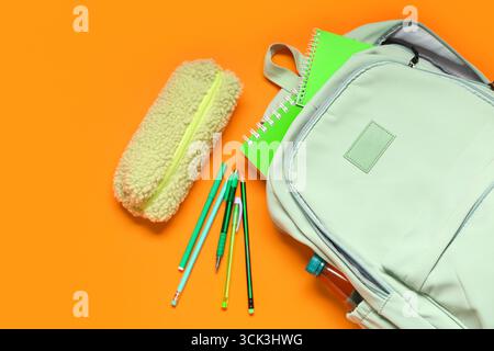 Backpack with school supplies on orange background. Top view Stock Photo