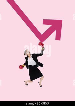 Minimalist pop art collage. Businesswoman in boxing gloves punching pink upward arrow with fierce face Stock Photo