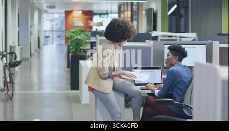 Reviewing documents and using laptops, coworkers wearing blazers working in office, with bicycle Stock Photo
