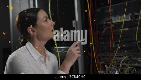 Pointing tech in white shirt inspecting server rack, cables in dimly lit data center, copy space Stock Photo