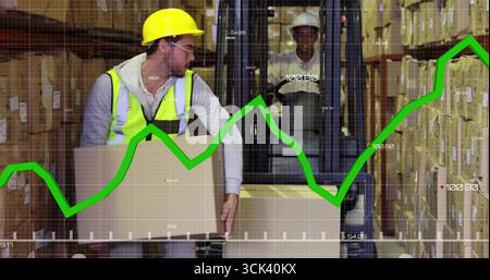 Worker in yellow helmet, safety vest lifting cardboard box in warehouse with forklift, green graph Stock Photo