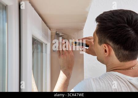 Caucasian plasterer man with a spatula applying finishing putty on a window opening Stock Photo