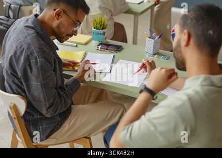 Young Adult Men Collaborating on Language Exercises in Classroom Setting Stock Photo