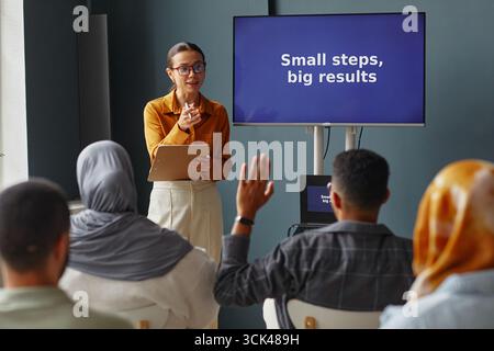Young Woman Teaching Diverse Adult Students in Language School Classroom Stock Photo