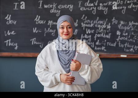 Young Adult Middle Eastern Woman Holding Notebook Smiling in Classroom Stock Photo