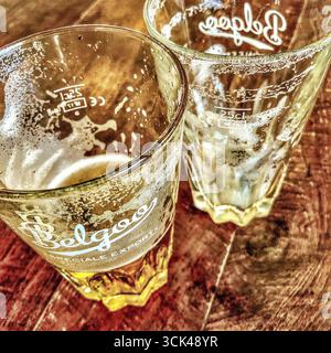 Two almost empty "Belgoo" beer glasses on bistro table - Brussels, Belgium. Stock Photo