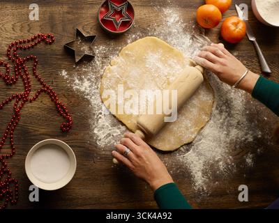 Women's hands roll out a sponge cake for a Christmas cake Stock Photo