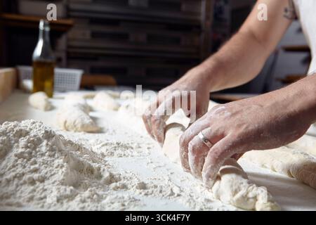 Baker kneads dough on a floured work surface Stock Photo
