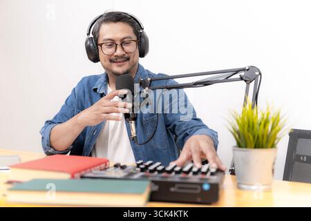 Close-up of young man recording podcast with microphone and headphones in studio. Concept of digital media, online communication, and modern content c Stock Photo