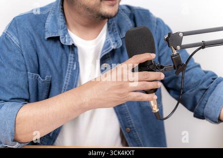 Close-up of young man recording podcast with microphone and headphones in studio. Concept of digital media, online communication, and modern content c Stock Photo