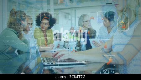 Using tablet and laptops team wearing casual wear analyzing code overlays in office with data icons Stock Photo