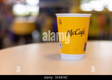 Kerpen, Germany - August, 9, 2025: Yellow McCafe cup on a table in McDonalds interior Stock Photo
