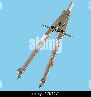 A metallic compass used for drawing circles and measuring distances in technical drawings. Stock Photo