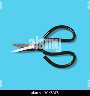 A pair of black-handled scissors with sharp metal blades, commonly used for cutting various materials. Stock Photo