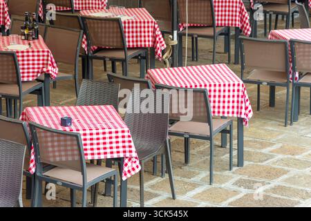 An outdoor caf with empty tables covered with red and white tablecloths Stock Photo