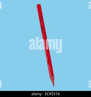 A red pencil with a sharpened tip, commonly used for writing or drawing. Stock Photo