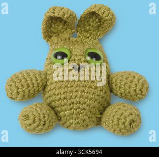 A cute crocheted bunny with large green eyes, designed as a playful decorative item or a toy. Stock Photo