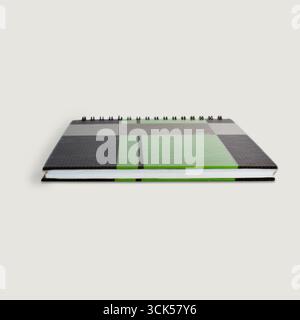 A closed notebook featuring a modern design with a green and black color scheme, ideal for note-taking and planning. Stock Photo
