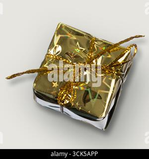 A shiny golden gift box wrapped in decorative paper and tied with a glittery ribbon, perfect for celebrations. Stock Photo