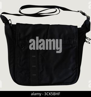 A black messenger bag with a shoulder strap and front pocket, designed for carrying personal items. Stock Photo