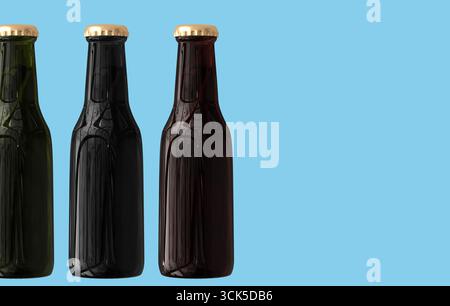Three glass bottles in varying colors, designed for beverages, featuring gold caps. Stock Photo
