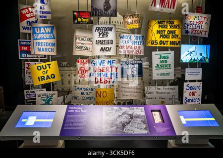 Smithsonian National Museum Of American History Protest Signs Washington DC // WASHINGTON DC — Protest signs from various demonstrations are displayed at the Smithsonian National Museum of American History, showcasing citizen participation and debate throughout American history. The exhibit, titled American Democracy: A Great Leap of Faith, explores the nation's formation to the present day. It features signs from movements advocating for D.C. statehood, the Freedom March, and against the war in Iraq. Other signs address issues like apartheid, immigration, and equality, reflecting diverse voic Stock Photo