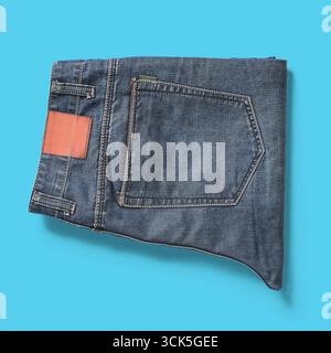 A folded pair of denim jeans showcasing the back pocket and waistband. Stock Photo