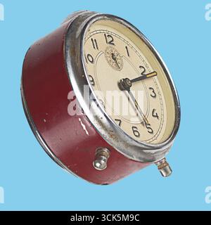 A vintage red alarm clock with a classic design, featuring a round face and traditional hour and minute hands. Stock Photo