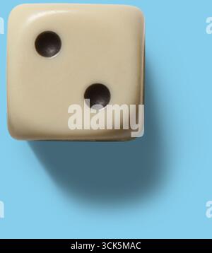 A close-up of a cream-colored die showing the number two. Stock Photo