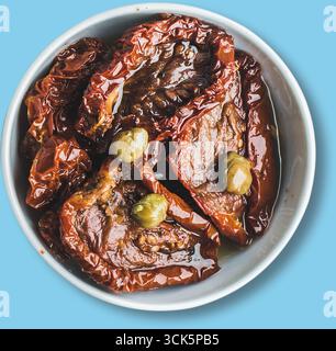A bowl of sun-dried tomatoes in olive oil, garnished with green olives, showcasing a rich, savory ingredient for various dishes. Stock Photo
